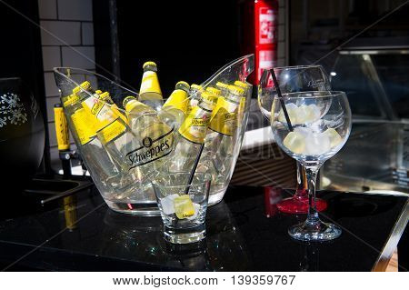 Key west, Fl, USA - March 30 2016: Schweppes Tonic Water bottles yellow color in glass with cold ice cubes on table near bocals of lemon beverage with drinking straw