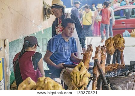 AZUAY, ECUADOR, OCTOBER - 2015 - Couple of chefs cooking traditional roasted cuy at street market in Azuay province Ecuador.