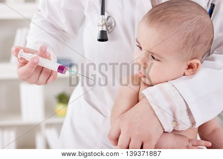 Female pediatrician vaccinating baby child, close up