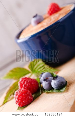 Fresh Summer Berries In Front Of Dessert In Blue Bowl
