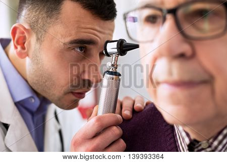 Otologist examining senior patient ear, close up