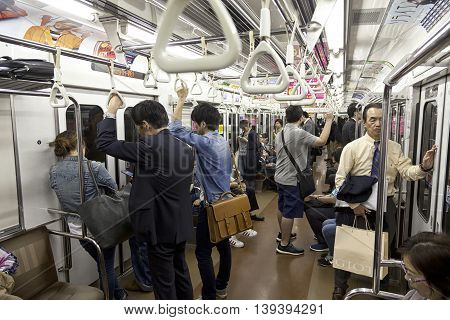 TOKYO- CIRCA MAY, 2016: Passengers traveling by Tokyo metro. Business people commuting to work by public transport in rush hour. Shallow depth of field photo