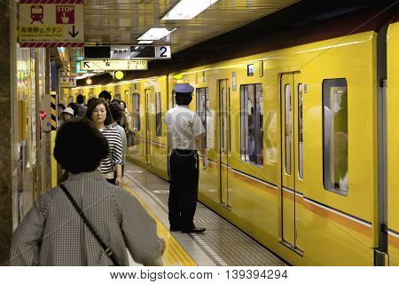 TOKYO- CIRCA MAY, 2016: Passengers traveling by Tokyo metro. Business people commuting to work by public transport in rush hour. Shallow depth of field photo