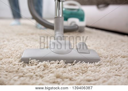 Woman with vacuum cleaner cleaning carpet at home