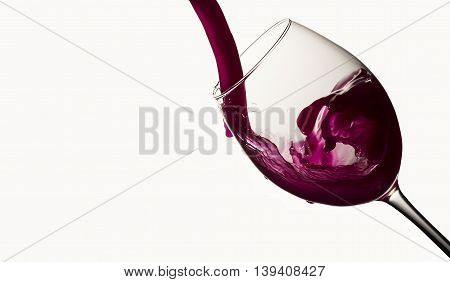 Red wine pouring in a wineglass on white background