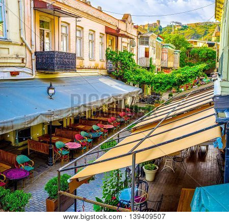 TBILISI GEORGIA - MAY 28 2016: The beautiful taverns' terraces are protected with canopies producing the shade to the guests on May 28 in Tbilisi.