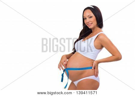 Smiling pregnant woman measuring girth tummy with meter tape during pregnancy