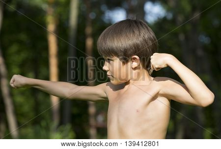portrait of a boy in nature which shows his muscles