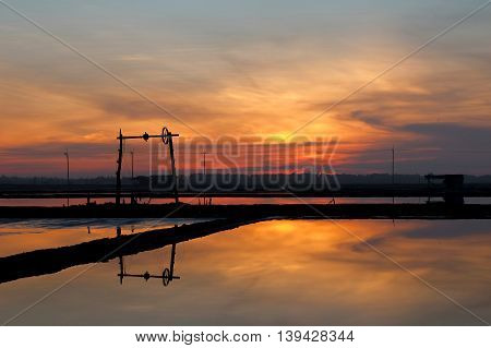SUNRISE AT SALT PAN
The salt pans or salt evaporation pond reflected the the windmill  in amber background because of sun rise in the early morning.