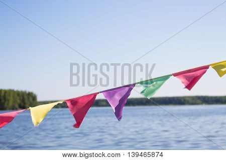 Multi-colored flags fluttering in the background of a large lake