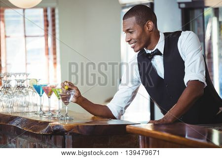 Bartender garnishing cocktail with olive on bar counter in bar