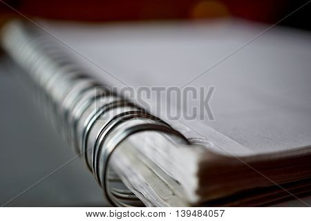Macro detail of a metal binding spiral of the white notepad on the silver surface