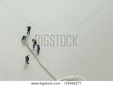 mini team of workers cut the white rope on isolate background and leave space for fill text wording - can use to display or montage on products or conceptual