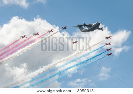 FARNBOROUGH, UK - JULY 17: Red Arrows formation flying team and an Airbus A400 transporter in the skies over Farnborough, UK on July 17, 2016
