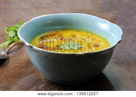 Yellow Lentil soup or Arhar Daal fry with the tadka of cumin seeds garlic and green chilies on a moody background