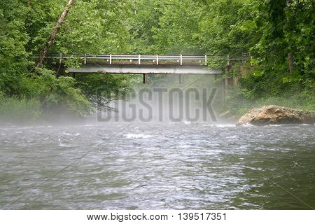 fog rises from the Nantahala River in North Carolina near a bridge.