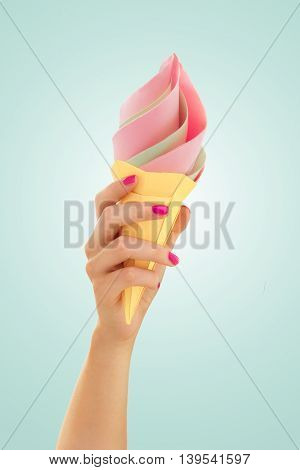 Fruit pink and green ice cream in the cone in hand origami paper desert on a blue background