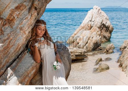 Beautiful young bride in white wedding dress on beach