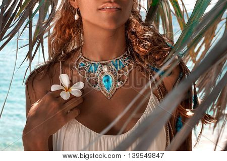 close up of beautiful young woman with necklace. Holding frangipani flower in her arm