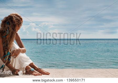 closeup photo of beautiful young bride legs with anklets. holding flower in her arms.