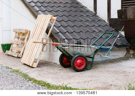 garden tools rakes trolley summer spring. red wheels. basement roof.