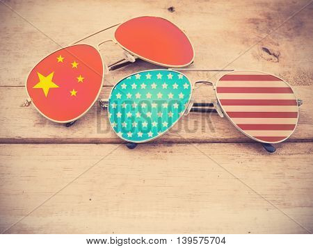 mirror glasses with American and Chinese flag pattern on wooden background vintage filter effect.