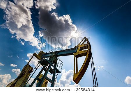Oil and gas well profiled on blue sky with cumulus clouds
