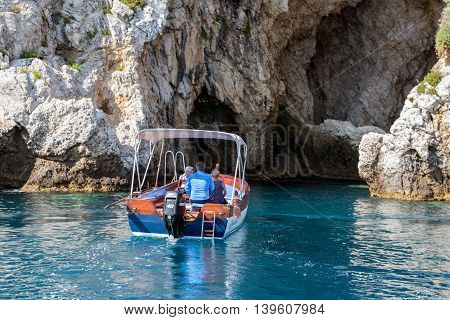 TAORMINA ITALY - MAY 21: Motorboat with people entering a cave at the rocky coast of Taormina on May 21 2016 at the island Sicily Italy