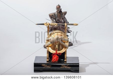 Kabuto helmet display with samurai statue in background.