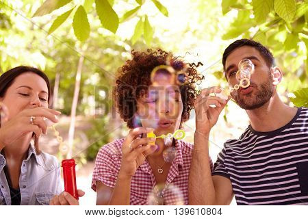 Three Happy Young Friends Blowing Bubbles