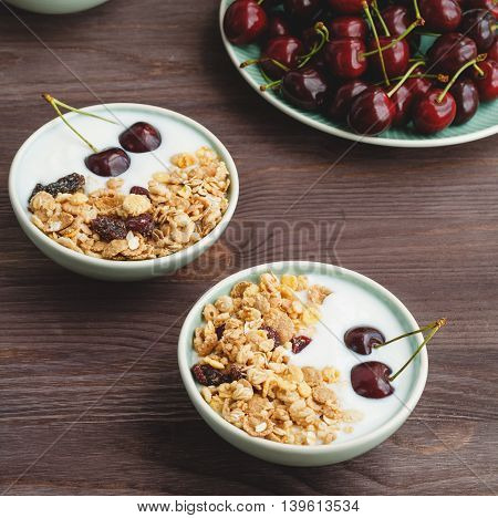 Healthy breakfast with muesli, yogurt and ripe cherries on a wooden rustic table