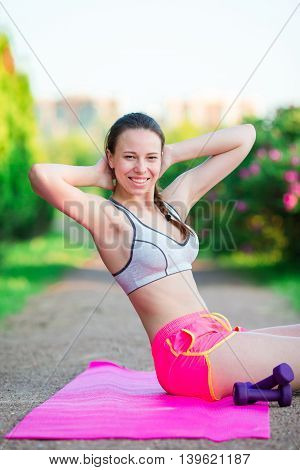 Fitness runner body closeup doing warm-up routine on beach before running, stretching leg muscles with standing single knee to chest stretch. Female athlete preparing legs for cardio workout.