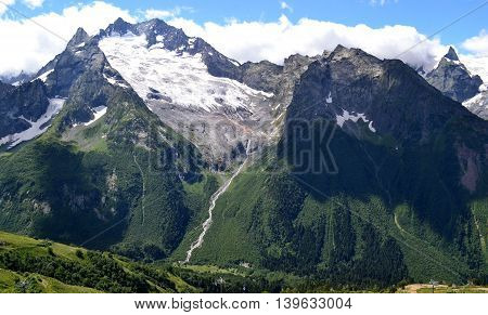 Sharp peaks of the mountains in Dombay on a background of white clouds. Karachay-Cherkessia in the basin of the Teberda in the North Caucasus (Russia). Photo taken on: July 26 Friday 2013