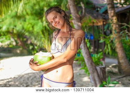 Photo young girl relaxing on beach with coconut. Smiling woman spending chill time outdoor summer Bali island. Indonesia Travel. Horizontal picture