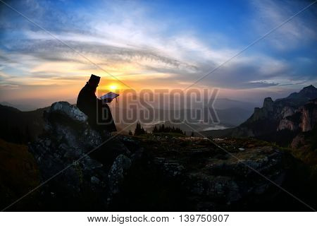 silhouette of priest reading in the sunset light, Romania, Ceahlau