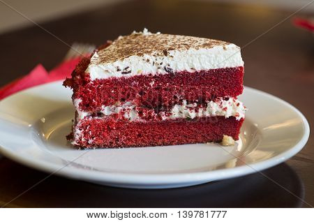 A slice of red velvet cake on a saucer.
