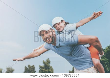 Carefree fun. Smiling young man piggybacking his son while standing outdoors