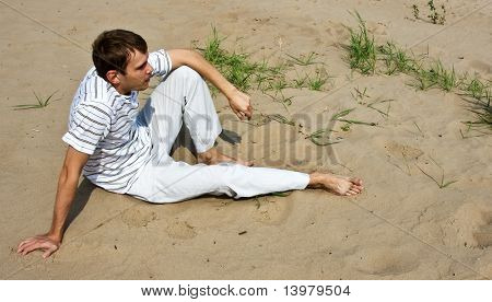 Homme des esprits faibles, assis sur le sable