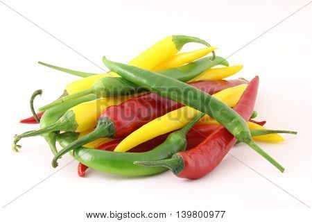 Big pile of chiili peppers in different colors yellow green and red isolated on white; also know as chilli peppers chille peppers or just chilli