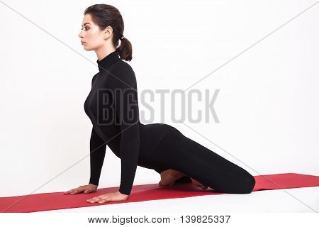 Beautiful athletic girl in black suit doing yoga. simhasana asana lion pose. Isolated on white background.