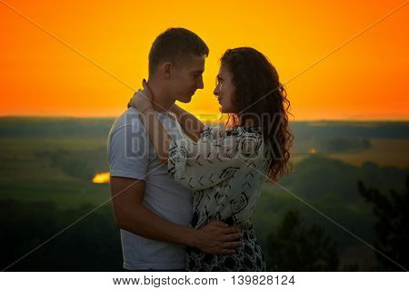 romantic couple at sunset on bright yellow sky background, love tenderness concept, young adult people