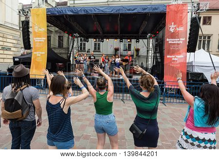 CRACOW POLAND - JULY 24 2016: Pilgrims of World Youth Day sing and dance on the St. Maria Magdalena Square in Cracow. Poland