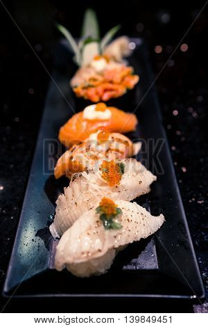 Dish of various sushi types selective focus point with blur depth of field effect dark atmosphere