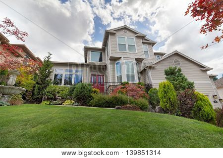 Front lawn of traditional house with manicured landscaping water fountain green grass plants trees shrubs