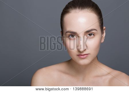 Beauty fashion vogue style face of caucasian brunette with elegant make-up blue eyes natural lips touching perfect skin. Close-up studio portrait isolated. Black background with grey spot. Toned.