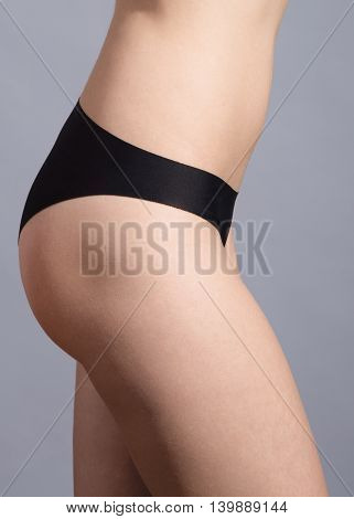 Close up photo of slim woman's body in black lingerie on gray background