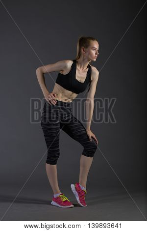 Body of slim female in activewear doing posin on gray low key perfect sport woman