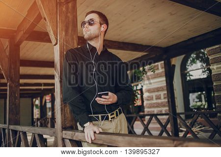 A guy in a nice town, walking, listening to music and taking pictures themselves on the phone