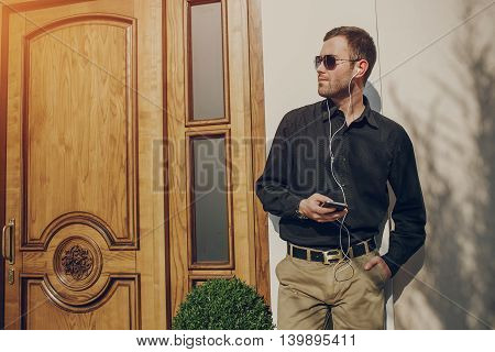 A guy in a nice town, walking, listening to music and taking pictures themselves on the phone