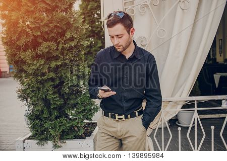 A guy in a nice town, walking, listening to music and taking pictures themselves on the phone
